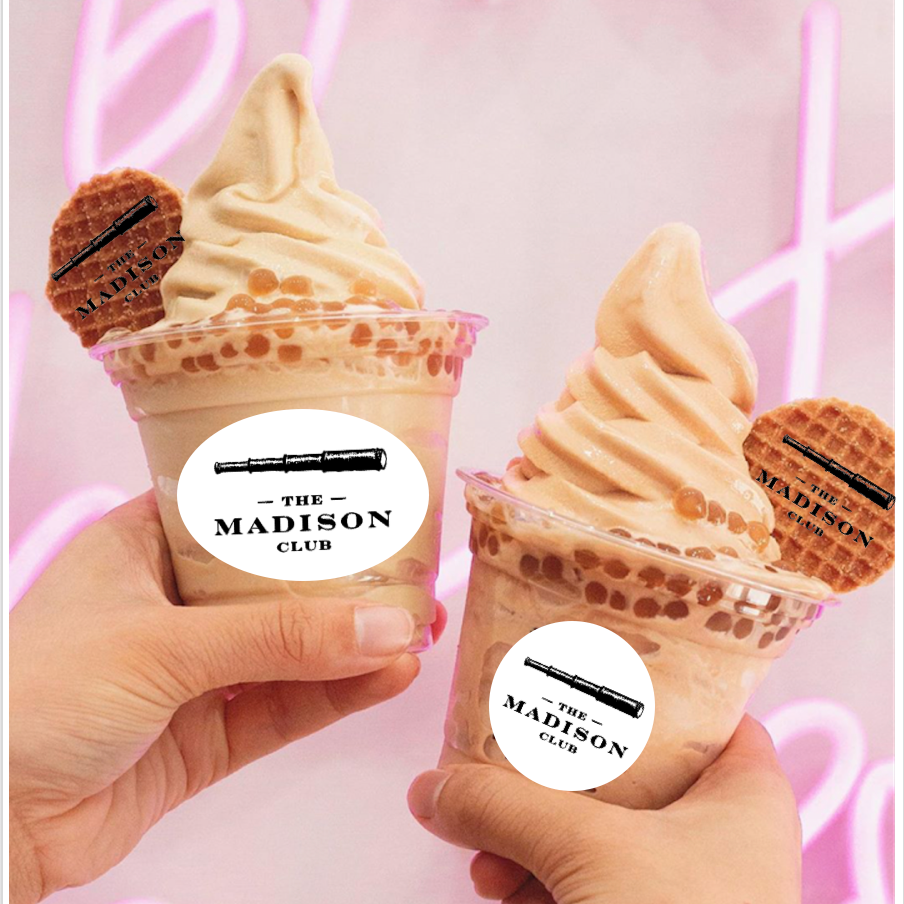 Two soft serve ice cream cones with branded mini wafers held by hands, branded 'The Madison Club' on a pink background.