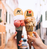 Two ice cream cones held by hands with a blurred background