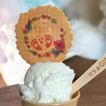 Ice cream in a paper cup with 'It's a Girl' sign and floral design on top.